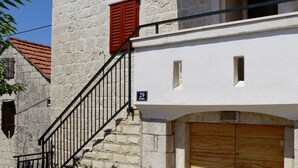 A stone building with a wooden door and a staircase leading to a balcony. - A2 - Studio With Balcony, Just 3 min to the Beach (Okrug)