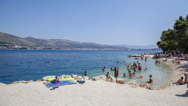 A beach with people swimming and sunbathing, a rocky shoreline, and a clear blue sky. - A2 - Studio With Balcony, Just 3 min to the Beach (Okrug)