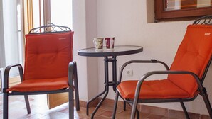 A room with two orange chairs, a small round table, and a window with blinds. - A2 - Studio With Balcony, Just 3 min to the Beach (Okrug)