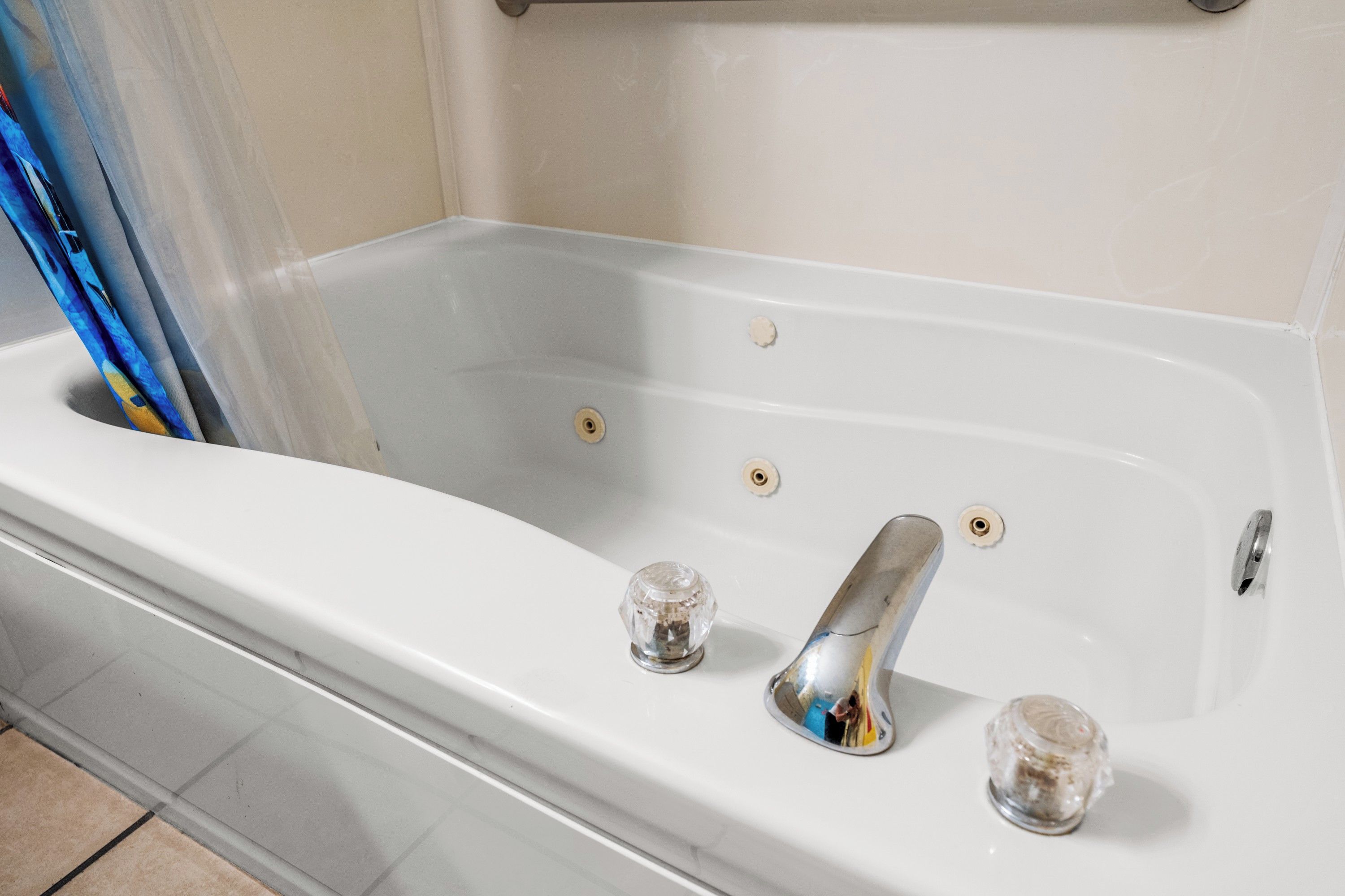A white bathtub with a chrome faucet and two glass bottles.