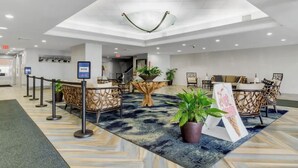 Eine moderne Lobby mit einer Rezeption, einer Sitzecke und einem großen Baumstamm als Mittelpunkt.