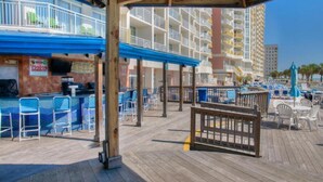 Un área de bar junto a la playa con asientos exteriores y una piscina.