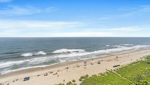 A beach with a clear sky, waves, and people.