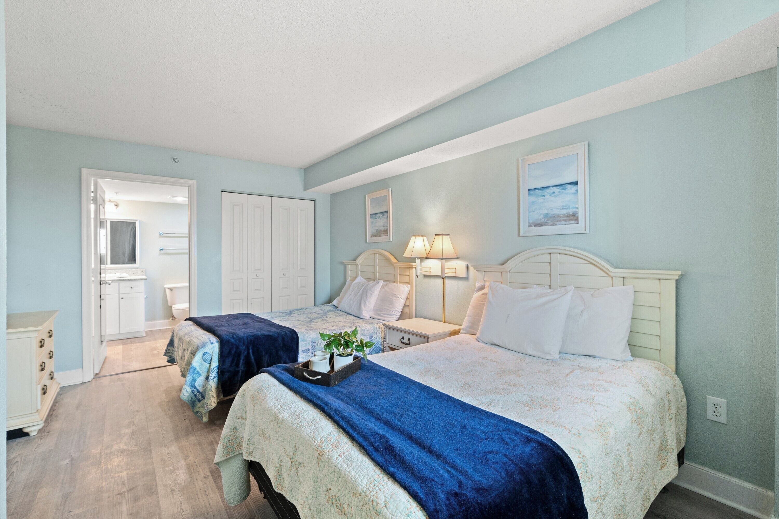 Une chambre avec deux lits, une commode et une porte donnant sur une salle de bain.
