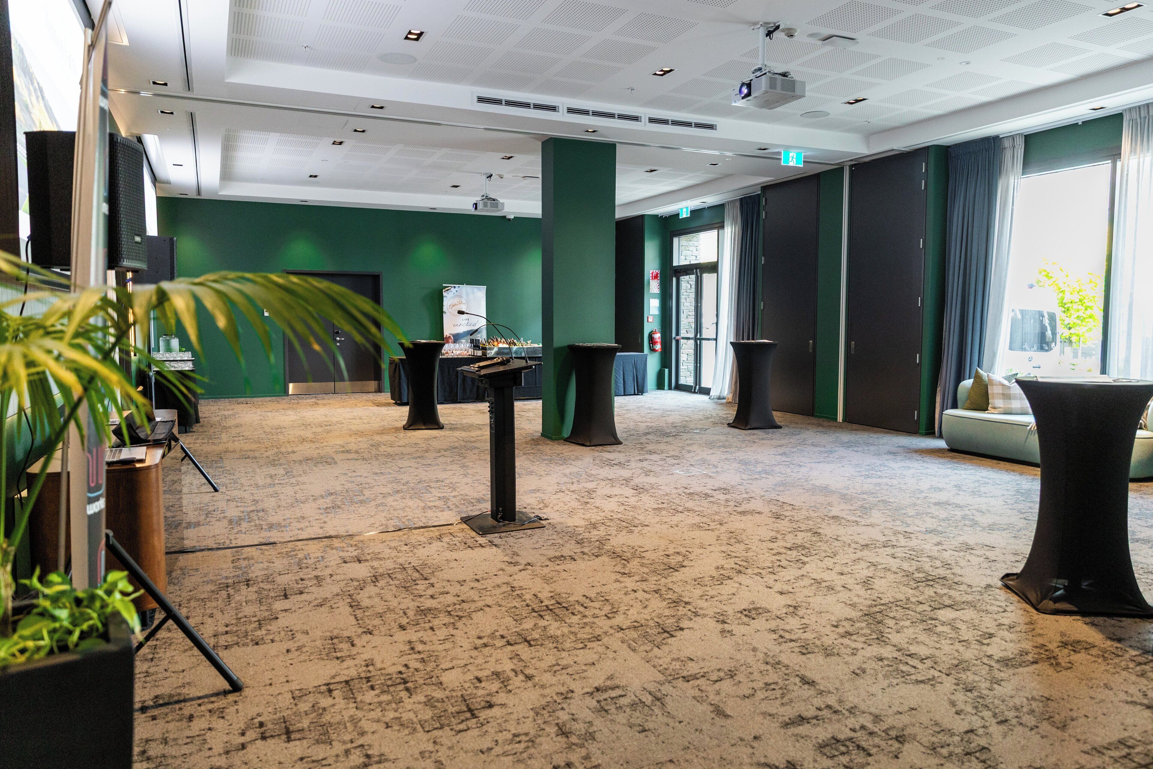 A spacious lobby with a green wall, a stage, and a seating area.