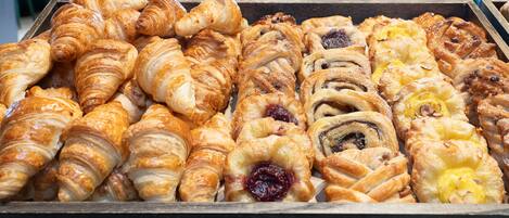 Uma bandeja com diversos doces, incluindo croissants e pastéis recheados com fruta.