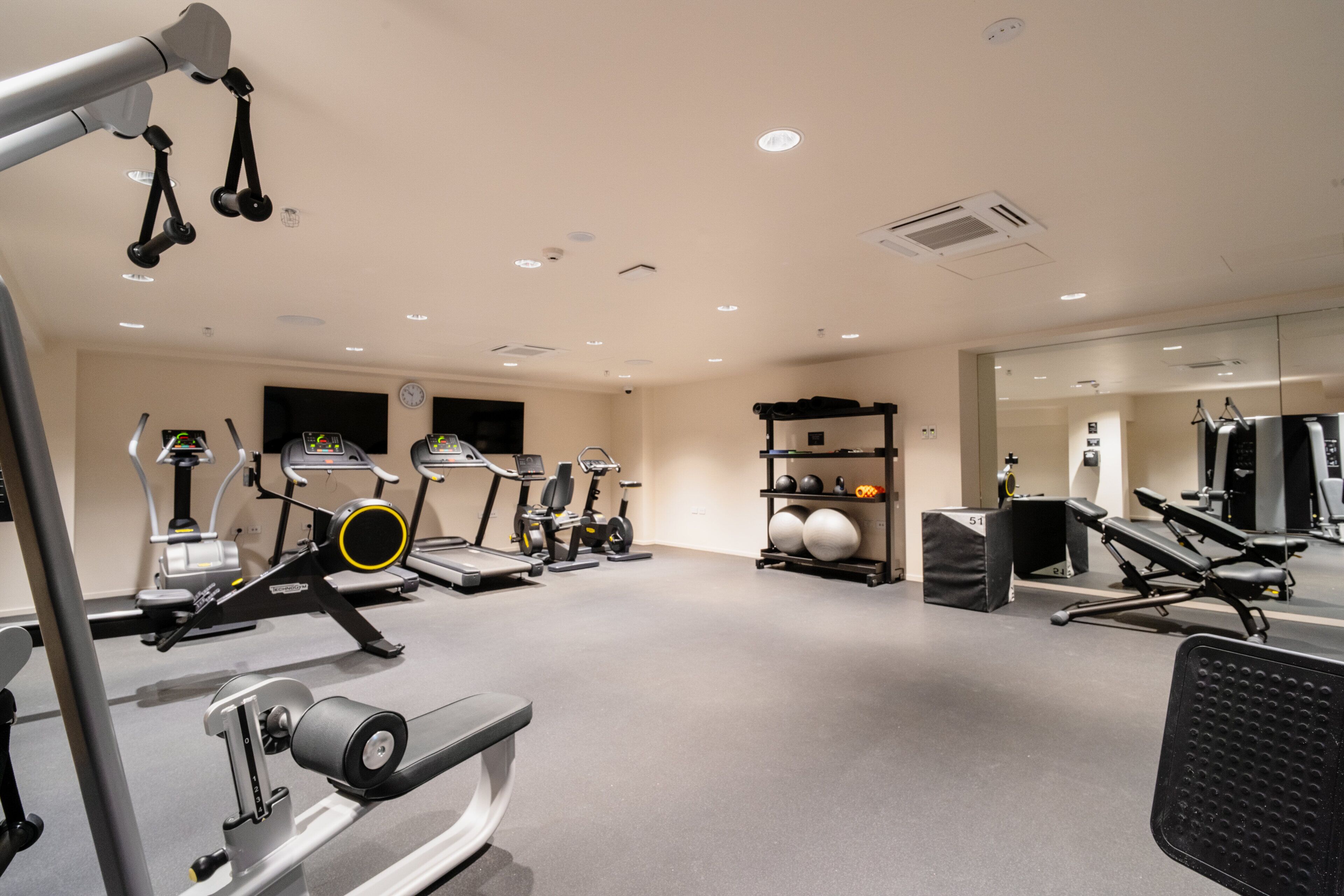 A gym with various exercise equipment, including treadmills, stationary bikes, and weight machines.