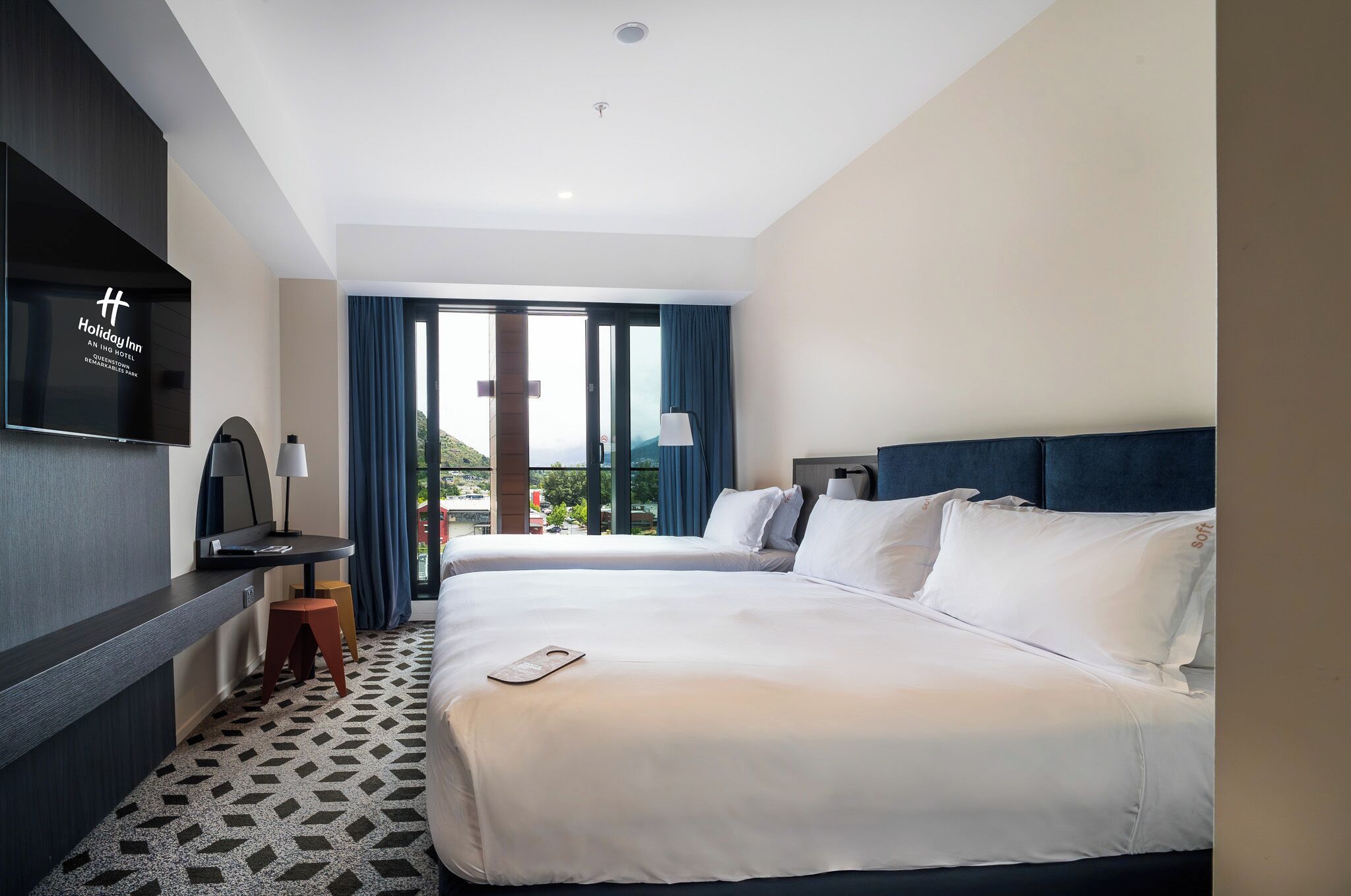 Una habitación de hotel con cama, escritorio, televisión y vistas al exterior.