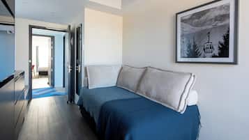 Una habitación de hotel moderna con una cama, un cuadro enmarcado en la pared y un pasillo que conduce a otra habitación.