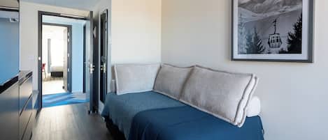 A modern hotel room with a bed, a framed picture on the wall, and a hallway leading to another room.