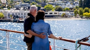 A couple embracing on a boat with a cityscape in the background. - Holiday Inn Queenstown Remarkables Park by IHG (Queenstown)