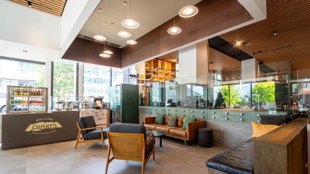 A modern bar area with seating, a counter with a logo, and a view of the outside. - Holiday Inn Queenstown Remarkables Park by IHG (Queenstown)