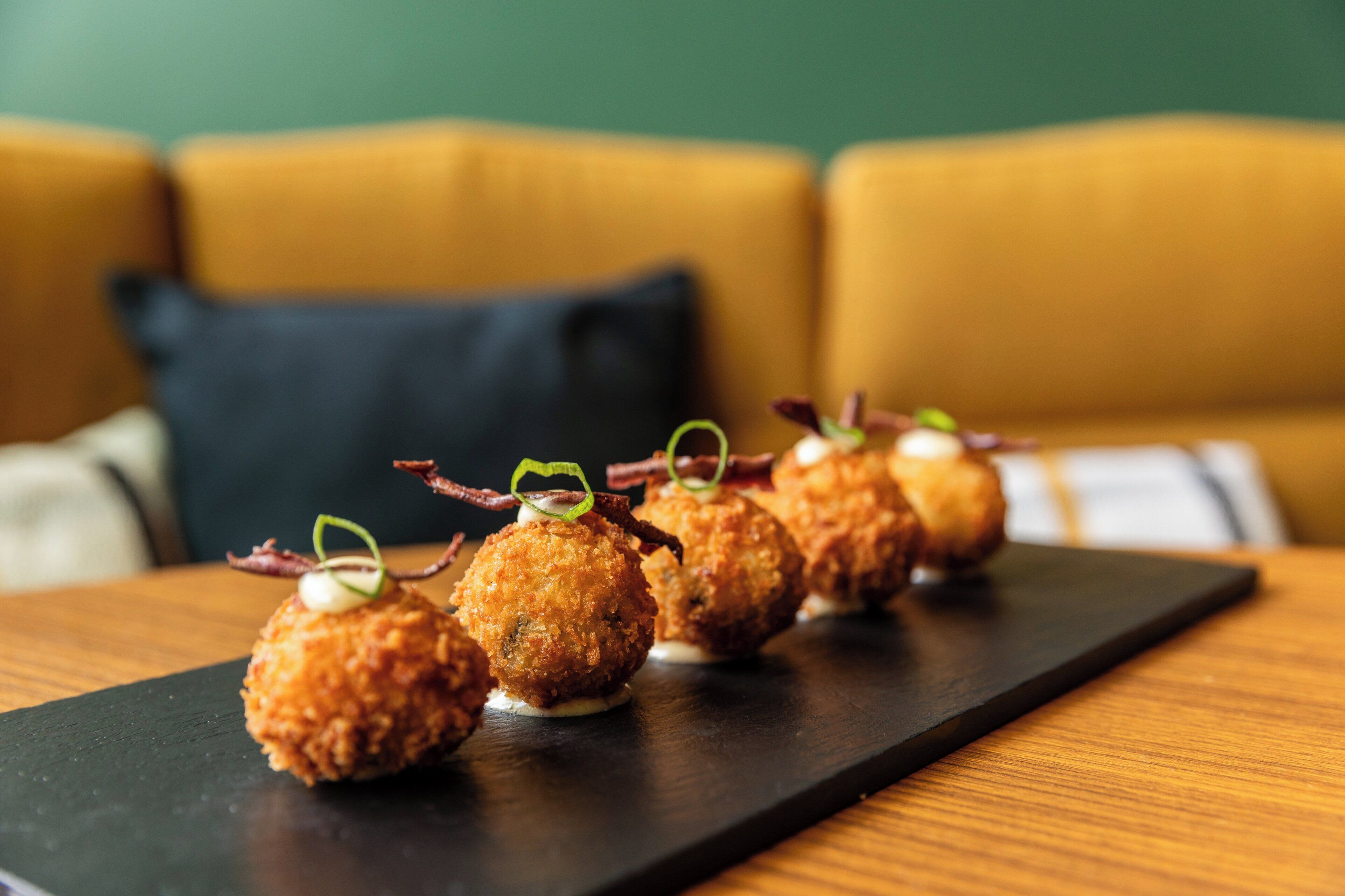 En række runde appetizers anrettet på en sort skiferfad.