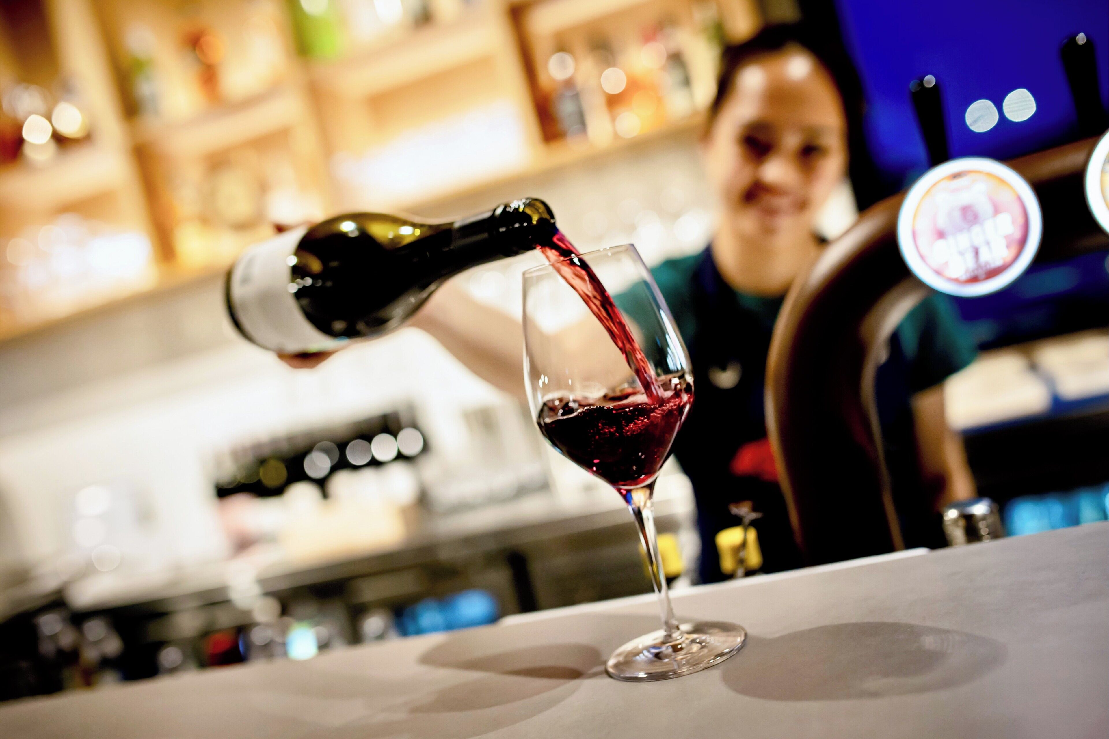 A bar setting with a wine bottle being poured into a glass.