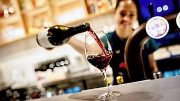 A bar setting with a wine bottle being poured into a glass.