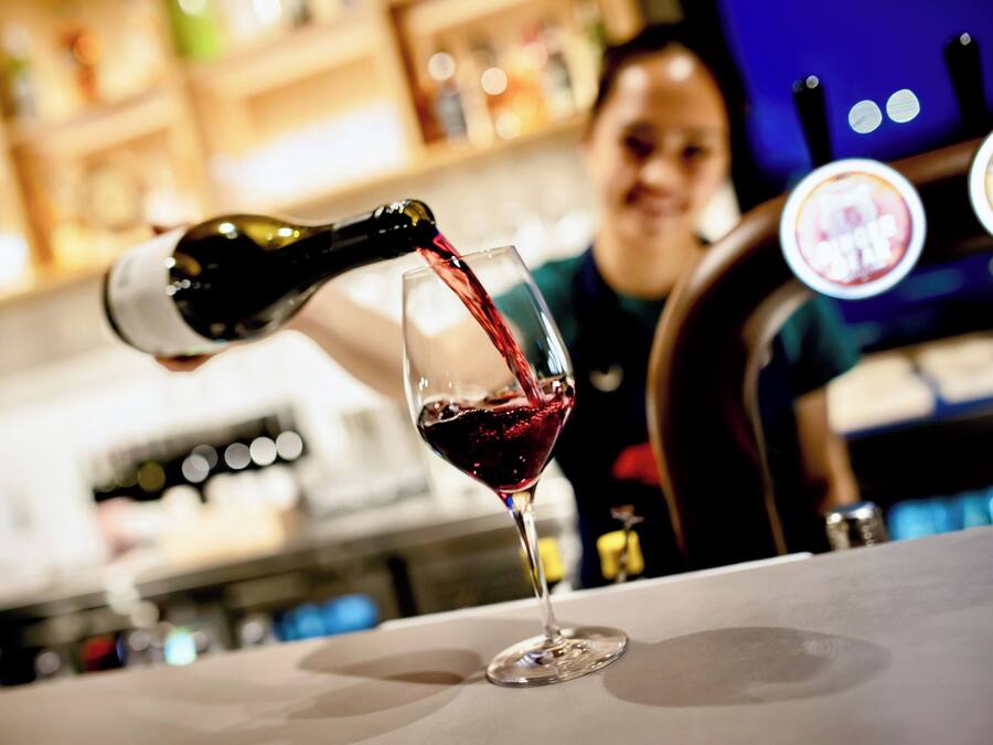 A bar setting with a wine bottle being poured into a glass.
