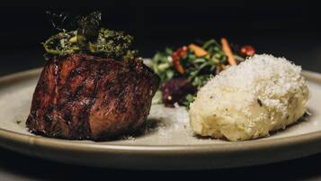 A plate with a grilled steak, a side of mashed potatoes, and a mixed vegetable salad.