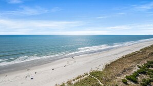 A beach with a clear sky, sandy shore, and a few people walking. - Bay Watch 1241-1BR/1BA Oceanfront Condo in North Myrtle Beach (North Myrtle Beach)