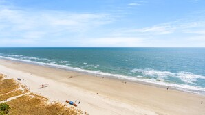 A beach with a lifeguard tower, sandy shore, and ocean waves.