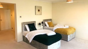 A hotel room with two beds, each with a headboard, a bedside table with lamps, and a wall-mounted artwork. - Spacious 3BR Home in Bedford for Big Groups (Bedford)