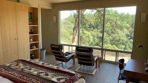 A bedroom with a large bed, two chairs, a desk, and a window with a forest view. - VIEWS!!  Last Minute/Longer Stay SPECIALS! (Ukiah Valley)