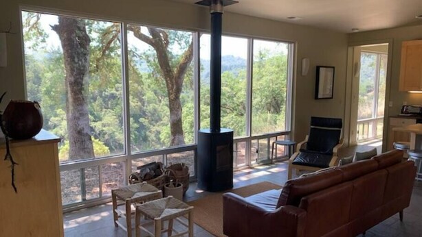 A spacious living room with a large window, a fireplace, a sofa, and a dining area. - VIEWS!!  Last Minute/Longer Stay SPECIALS! (Ukiah Valley)