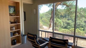 A room with a large window, two chairs, a wooden shelf with decorative items, and a door. - VIEWS!!  Last Minute/Longer Stay SPECIALS! (Ukiah Valley)
