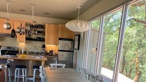 A modern kitchen with wooden cabinets, stainless steel appliances, and a large dining table with chairs. - VIEWS!!  Last Minute/Longer Stay SPECIALS! (Ukiah Valley)