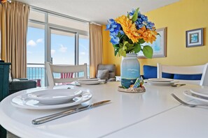 A dining table set with plates, cutlery, and a vase of flowers.
