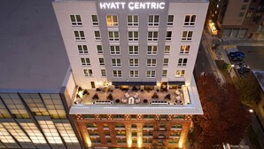 Ein mehrstöckiges Gebäude mit der Aufschrift "HYATT CENTRIC". Es verfügt über eine Dachterrasse mit Außenbestuhlung und einer unteren Ebene mit Ziegelverkleidung.