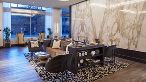 Ein modernes Wohnzimmer mit einer Couch, Sesseln, einem Couchtisch und einer Marmorwand.