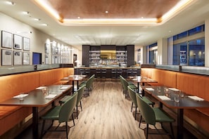Un restaurant avec des banquettes et des tables, un bar et des tableaux encadrés aux murs.