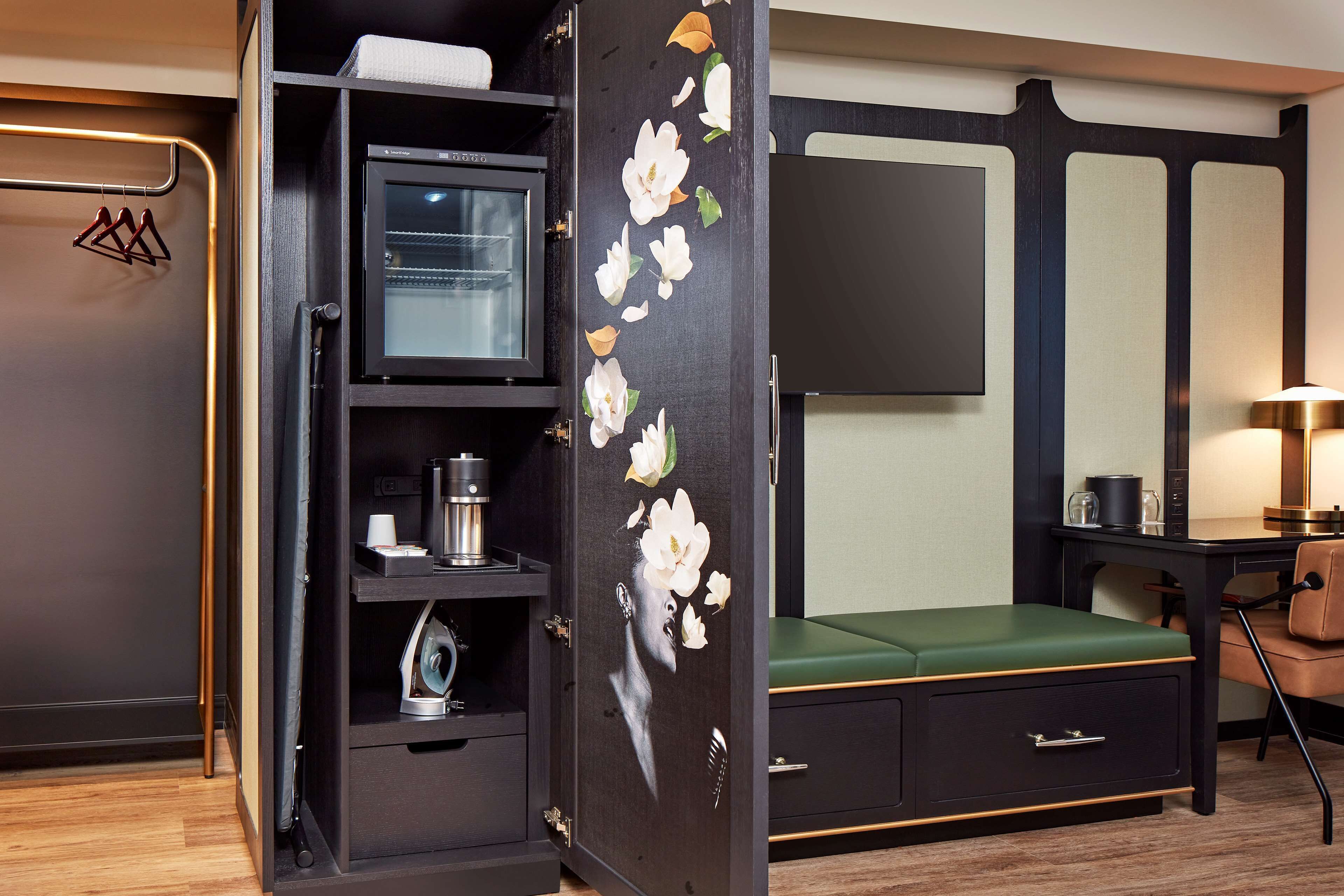 Habitación de hotel compacta con cama, escritorio y armario con diseño floral.