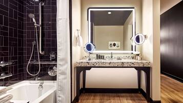 Een moderne badkamer met een bad, een douche, een wastafel met spiegel en een houten vloer.