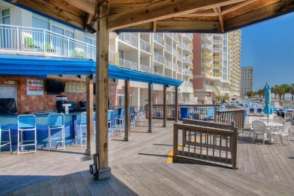 A beachside bar area with outdoor seating and a pool.