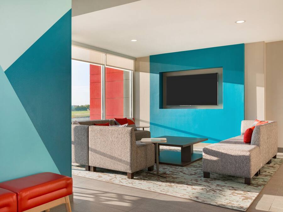 A modern living room with a sofa set, a coffee table, and a flat-screen TV mounted on the wall.