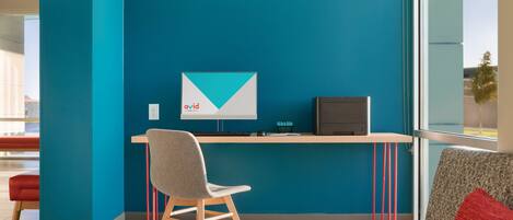 Un espace de travail moderne avec des murs de couleur turquoise, un bureau, une chaise et un canapé.