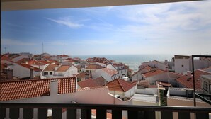 Un paysage urbain côtier avec des bâtiments aux toits de tuiles rouges et une vue sur la mer.