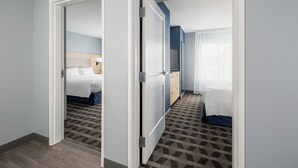 A hotel room with a bed, bedside table, and a window with curtains. - TownePlace Suites by Marriott Rochester Mayo Clinic Area (Rochester)