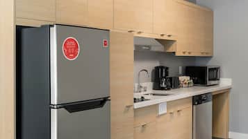 Une cuisine moderne avec des meubles de couleur bois clair, un réfrigérateur en acier inoxydable, un four à micro-ondes et un lave-vaisselle.