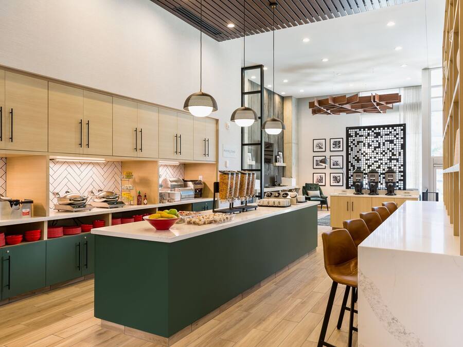Una cocina moderna con una isla central, armarios de madera e iluminación colgante.