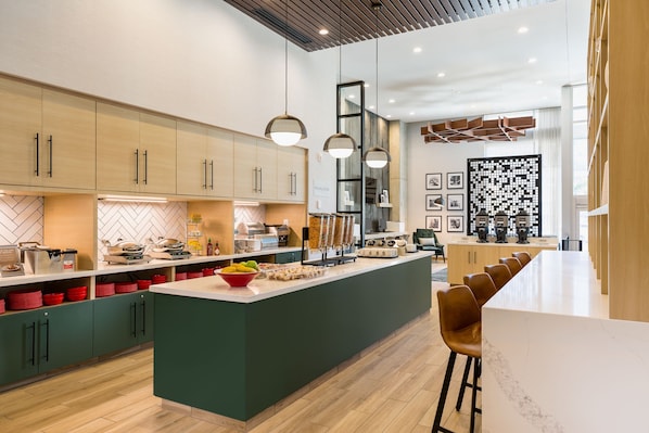 A modern kitchen with a central island, wooden cabinets, and pendant lighting.