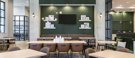 A modern conference room with a large table, chairs, and a flat-screen TV.