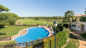 Une piscine avec vue sur un terrain de golf et une maison en arrière-plan.