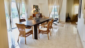Un espace repas avec une longue table, des chaises en osier et une lampe moderne.