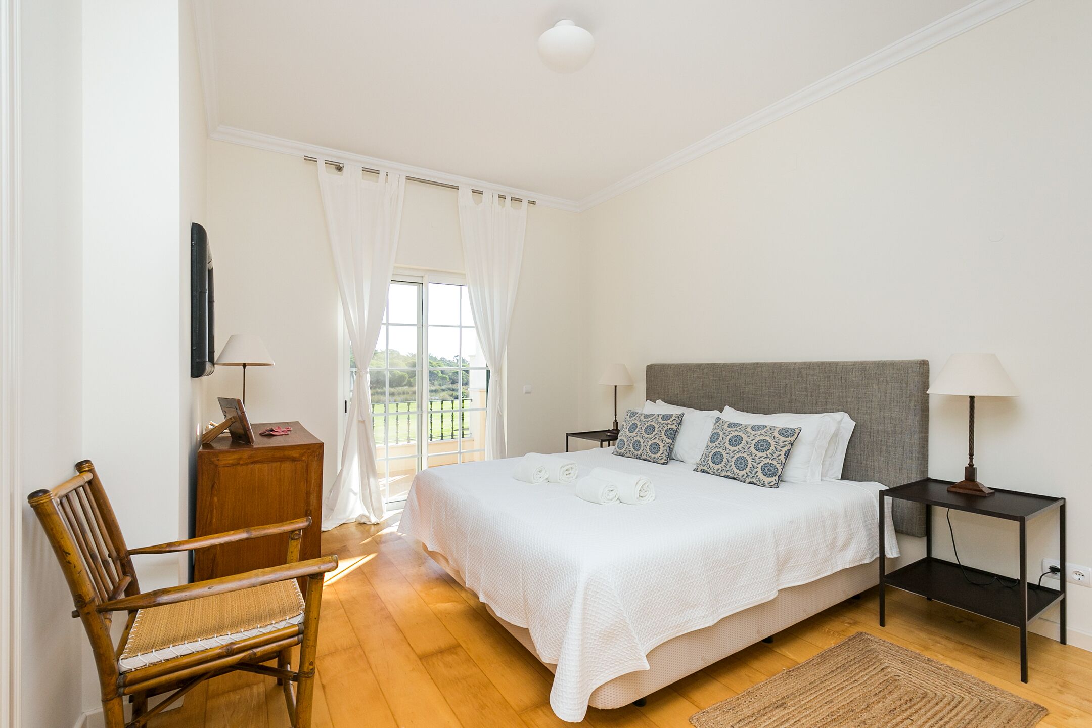 Une chambre à coucher comprenant un lit, une chaise, une table de chevet et un bureau avec une lampe.