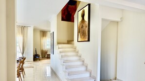 Un intérieur moderne avec un escalier, un coin repas et une œuvre d’art encadrée accrochée au mur.