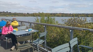 A lakeside seating area with metal chairs and tables, overlooking a calm lake.