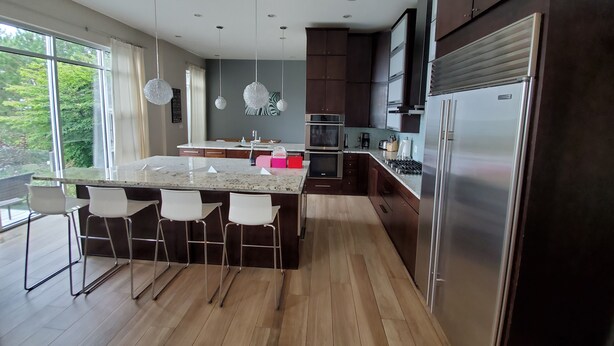 A modern kitchen with a central island, stainless steel appliances, and a large window offering a view of greenery. - Sunset and Serenity (Benton Harbor)