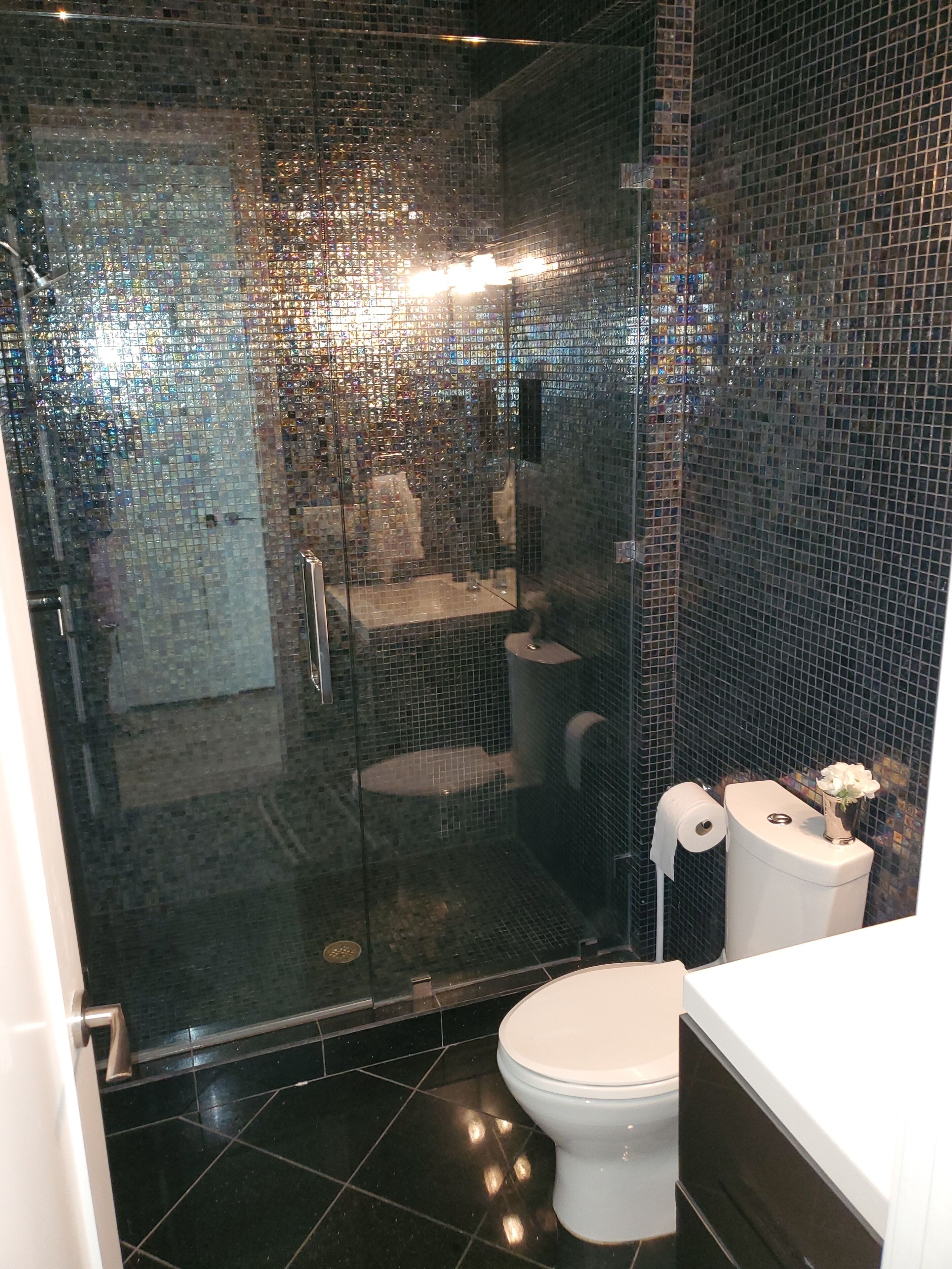 Une salle de bain moderne avec une douche à parois de verre, des toilettes blanches et un lavabo.